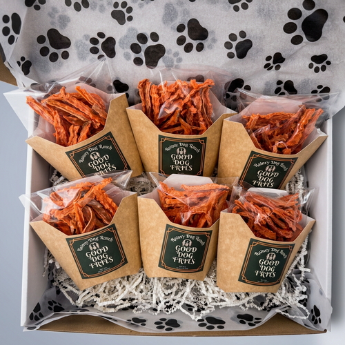 Box of dog treats with branded packaging on a paw print patterned surface